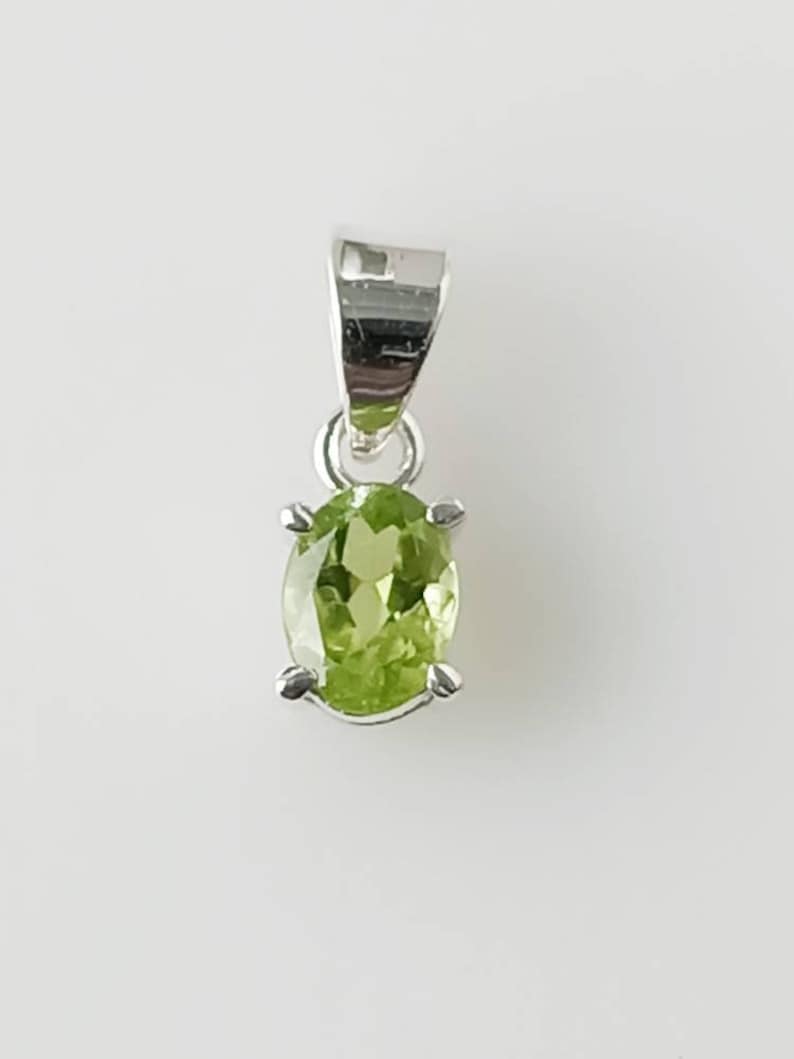 May include: A silver pendant with a green oval gemstone.