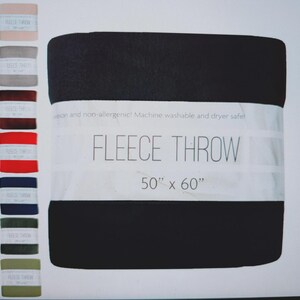 Puede incluir: Una manta polar negra, de 127 cm x 152 cm, con una banda blanca con la inscripci&oacute;n "FLEECE THROW". En el lado izquierdo de la imagen se muestra una carta de colores de opciones de mantas polares.