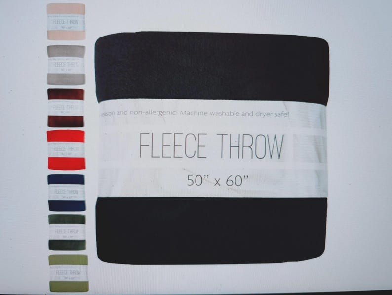 Puede incluir: Una manta polar negra, de 127 cm x 152 cm, con una banda blanca con la inscripci&oacute;n "FLEECE THROW". En el lado izquierdo de la imagen se muestra una carta de colores de opciones de mantas polares.