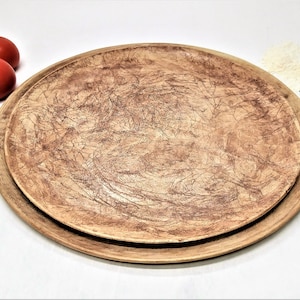 May include: A set of two brown ceramic plates with a textured surface. The plates are round and have a rustic look.