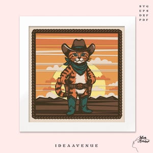 May include: A framed illustration of a cowboy cat with orange and brown fur, wearing a brown hat, blue bandana, and boots. The cat has two holstered guns and stands against a sunset backdrop. The text "IDEA AVENUE" is at the bottom.