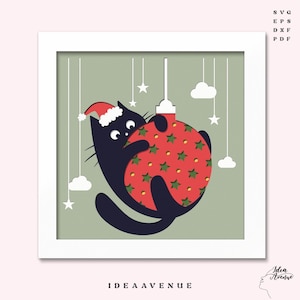 May include: A black cat wearing a Santa hat embraces a red Christmas ornament with green star cutouts. The artwork is set against a light green background with white stars and clouds, framed in a white square. The text "IDEA AVENUE" is at the bottom.