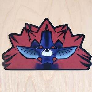 May include: A sticker featuring a stylized illustration of a red and blue creature with sharp teeth and glowing red eyes. The creature is surrounded by a red, spiky halo.
