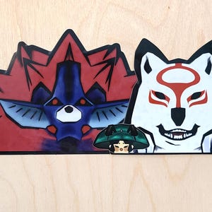 May include: Three vinyl stickers featuring anime characters. The first sticker is red and blue with a creature with a spiky red mane. The second sticker is white with a wolf-like creature with a red mask. The third sticker is green and black with a character with a green hat.