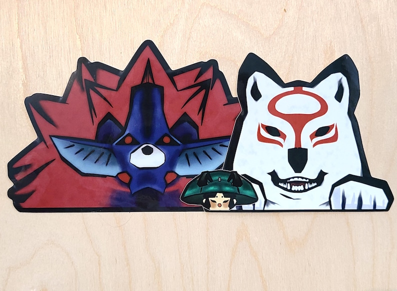 May include: Three vinyl stickers featuring anime characters. The first sticker is red and blue with a creature with a spiky red mane. The second sticker is white with a wolf-like creature with a red mask. The third sticker is green and black with a character with a green hat.