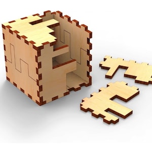 Może przedstawiać: Drewniana skrzynka z puzzlami o geometrycznym wzorze. Skrzynka jest otwarta, a elementy są rozrzucone wokół niej. Skrzynka jest wykonana z jasnego drewna z brązowym odcieniem.