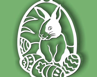 May include: White paper cut-out of a bunny rabbit sitting in a nest of Easter eggs. The bunny is surrounded by eggs with intricate designs.