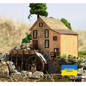 May include: A wooden model of a watermill with a working water wheel. The mill is painted brown and has a red door. The model is set on a bed of rocks and greenery. The text "Ukraine Store" is visible in the lower right corner of the image.