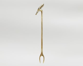 Puede incluir: Un tenedor de metal dorado con un mango en forma de pájaro. El tenedor tiene dos púas y mide aproximadamente 30 cm de largo.