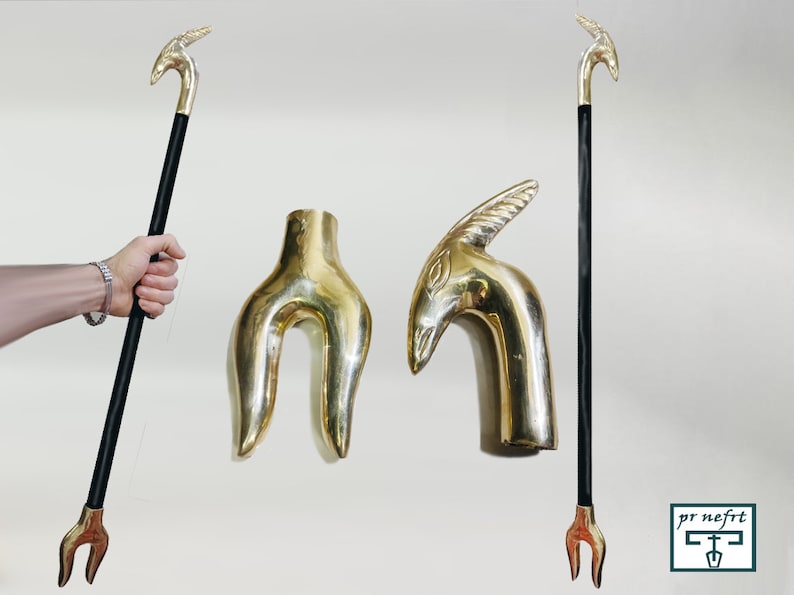 May include: Two gold-toned walking stick handles, one shaped like a bird's head and the other like a forked branch. The handles are shown next to a black walking stick with a gold-toned bird's head handle.