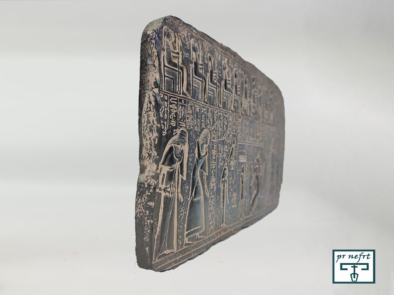 May include: A black stone relief with hieroglyphics and figures of people. The relief is carved with intricate details and depicts a scene from ancient Egyptian history.