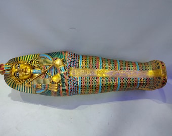 May include: A gold sarcophagus with intricate details, including a blue and green patterned design, and a depiction of a pharaoh's face. The sarcophagus is a decorative object.