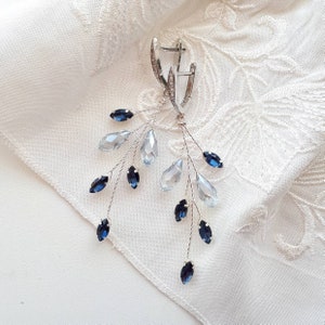 May include: Silver earrings with a delicate branch design featuring blue and clear crystal accents.