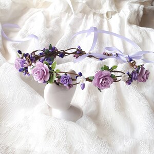 May include: A purple and white flower crown with a satin ribbon. The crown is made of artificial flowers and is perfect for a wedding or other special occasion.