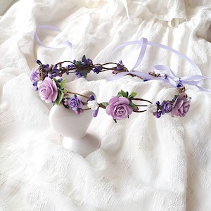 May include: A purple and white flower crown with a delicate floral design. The crown is made with artificial flowers and is perfect for a special occasion.
