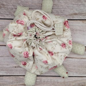 May include: A white ceramic mug with a black handle and the text "But First, Coffee" in a bold, black font. The mug is set against a blurred background, suggesting a cozy setting.