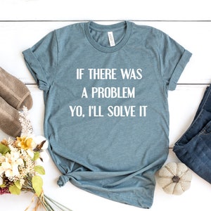 以下が含まれることがあります： 白い文字で「If there was a problem, yo, I'll solve it」とプリントされたターコイズブルーのTシャツです。