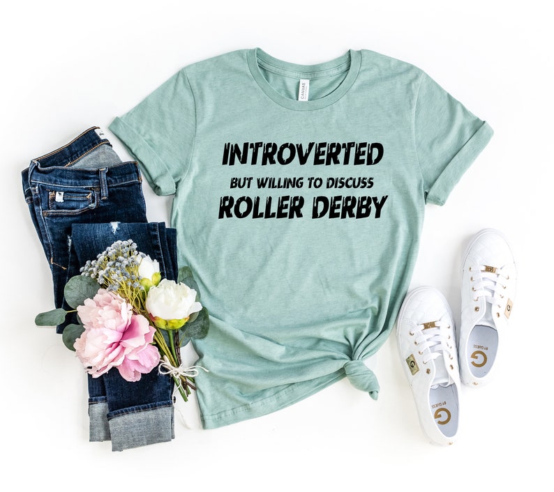 May include: A light blue t-shirt with the text "Introverted but willing to discuss roller derby" in black.