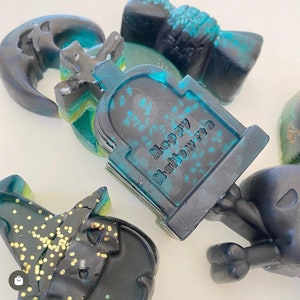 Puede incluir: Un juego de seis jabones con tem&aacute;tica de Halloween. Los jabones son negros y verdes con purpurina y presentan una variedad de dise&ntilde;os espeluznantes, que incluyen una luna creciente, una l&aacute;pida, un sombrero de bruja y una calavera. El jab&oacute;n de la l&aacute;pida dice "Happy Halloween".