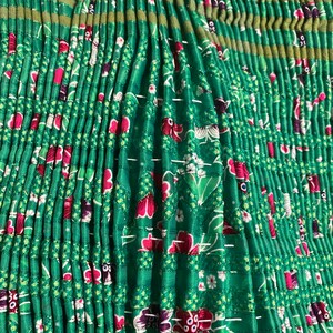 May include: Green fabric with a floral pattern and pleats. The fabric is gathered and sewn together to create a ruffled look.