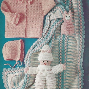 May include: A crochet baby set in pink and blue includes a cardigan, hat, blanket, and two stuffed toys. The blanket has a scalloped edge and a striped pattern. The toys are a cat and a doll.