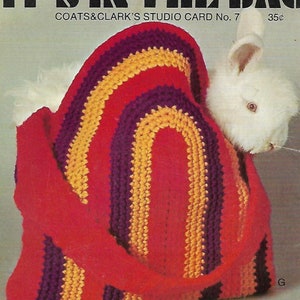 May include: A crocheted bag with red, purple, and yellow stripes. The bag is shaped like a half-circle and has a handle. A white rabbit is peeking out of the bag. The bag is labeled "It's in the bag" and "Coats & Clark's Studio Card No. 7 35¢".