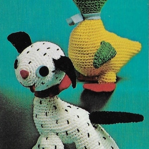 Puede incluir: Un juguete de perro dálmata de crochet blanco y negro con un lazo rojo y un juguete de pato de crochet verde y amarillo con una cinta blanca.