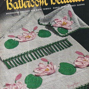 May include: A vintage crochet pattern book titled "Bathroom Beauties" with a cover featuring a white towel with green and pink crocheted water lily designs. The book is from Clark's O.N.T. J. & P. Coats and is priced at 10 cents.