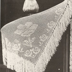 Peut inclure: Un châle en crochet blanc avec une bordure en franges. Le châle est drapé sur les épaules d'une personne.