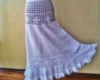 May include: White crochet skirt with a scalloped hem and intricate lace patterns. The skirt is displayed on a mannequin.