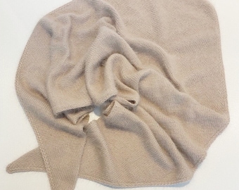 May include: A light beige knitted scarf with a triangular shape. The scarf is folded in half and has a soft, fuzzy texture.