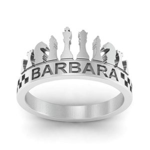 May include: A silver ring with a chess piece design and the name "BARBARA" engraved on the band.
