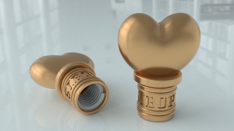 May include: Two gold-colored heart-shaped bottle stoppers with the word "STOP" engraved on the base.