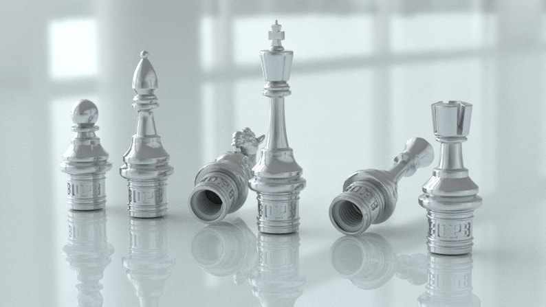 Pu&ograve; includere: Un set di sei pezzi degli scacchi argentati, tra cui re, regina, alfiere, cavallo, torre e pedone. I pezzi sono tutti in posizione caduta o inclinata, suggerendo una partita in corso.