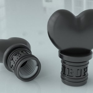 May include: Two black heart-shaped bottle stoppers with a threaded base. The stoppers have the words "Sir Up" engraved on the base.