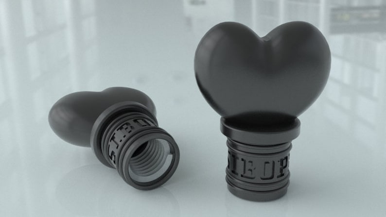May include: Two black heart-shaped bottle stoppers with a threaded base. The stoppers have the words "Sir Up" engraved on the base.