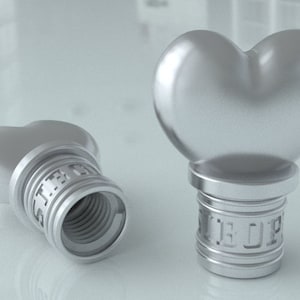 May include: Two silver heart-shaped bottle stoppers with threaded bases. The stoppers are made of metal and have a shiny finish.