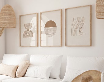 Puede incluir: Tres impresiones de arte abstracto minimalistas en marcos de madera, con dibujos de líneas marrones de formas geométricas, un sol y líneas onduladas, colgadas en una pared blanca sobre un sofá blanco con almohadas beige.