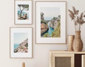 Puede incluir: Tres fotografías enmarcadas de paisajes costeros italianos. La foto superior muestra un puente sobre una estrecha entrada de agua. La foto del medio muestra un pueblo pequeño en un acantilado con vista al mar. La foto inferior muestra un árbol y un edificio en un acantilado con vista al mar.