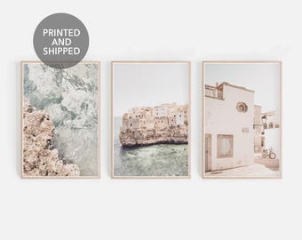 May include: Set of three printable art prints featuring coastal scenes. The first print shows a rocky cliff with turquoise water. The second print shows a white building with a red roof and a blue sky. The third print shows a white building with a red roof and a blue sky.