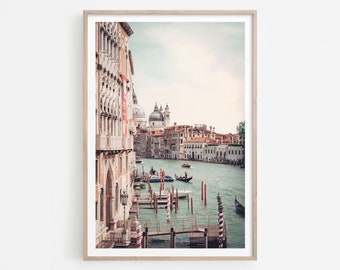 May include: A view of a canal in Venice, Italy. The canal is lined with buildings, and there are boats in the water. The sky is a light blue, and there are clouds in the sky.