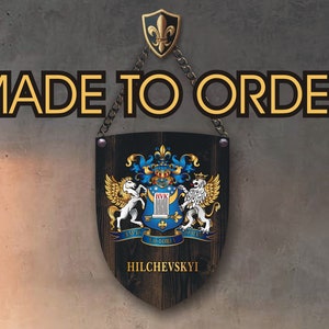 May include: A wooden shield-shaped sign with a family crest design. The sign is black with gold, blue, and white details, and the text "MADE TO ORDER" is across the top. The family name "HILCHEVSKYI" is at the bottom.
