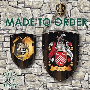 Op de afbeelding: Twee houten schilden met heraldische ontwerpen. Het schild aan de linkerkant heeft een zwart-gouden ontwerp met de naam "Allison" erop. Het schild aan de rechterkant heeft een rood-wit-gouden ontwerp met de naam "Singley" erop. Beide schilden hangen aan een stenen muur met een ketting en een fleur-de-lis.