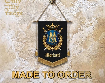 Puede incluir: Una pancarta negra con ribetes y borlas doradas cuelga de un gancho dorado. La pancarta presenta un escudo dorado con un escudo azul, una corona y dos espadas. El texto "Moriarty" está impreso en dorado debajo del escudo. La pancarta se hace por encargo.