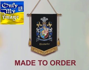Puede incluir: Un estandarte negro con un escudo familiar detallado, borlas doradas y el nombre "Unsdorfer". El estandarte está suspendido por una barra y un cordón dorados. El texto "MADE TO ORDER" se muestra en rojo.
