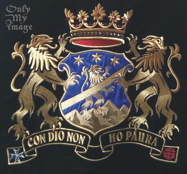 Puede incluir: Un escudo de armas bordado en oro con dos leones, un escudo con fondo azul y estrellas doradas, y una corona con joyas rojas. El escudo representa un le&oacute;n dorado y monta&ntilde;as. El escudo de armas incluye una cinta dorada con el texto "CON DIO NON HO PAURA".