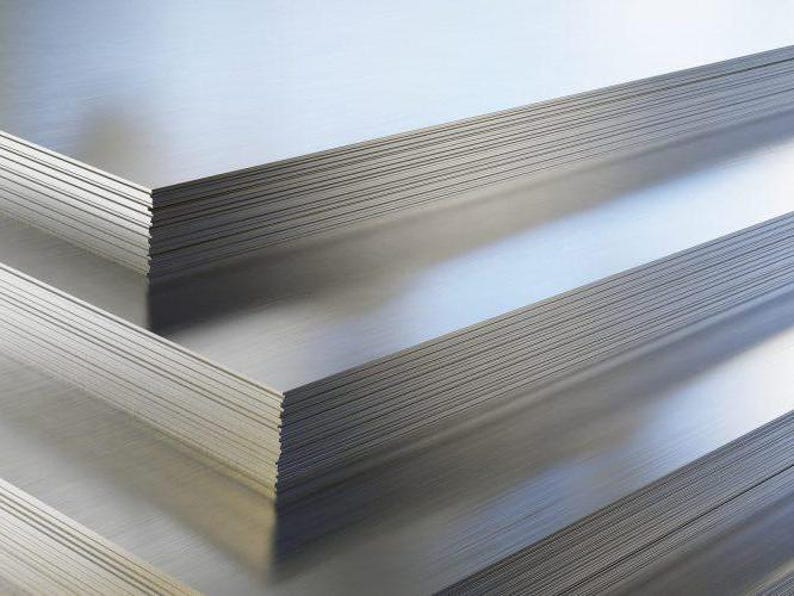 May include: A stack of silver metal sheets, likely used for construction or manufacturing.