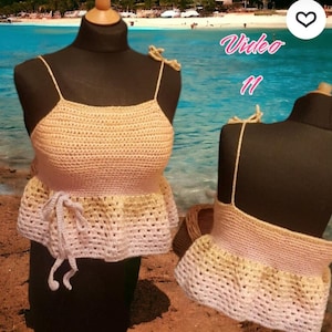 Puede incluir: Top de crochet beige hecho a mano con tirantes finos y peplum. El top se muestra en un maniqu&iacute;, con un segundo maniqu&iacute; en el fondo. El texto "Video 11" es visible en la esquina superior derecha.