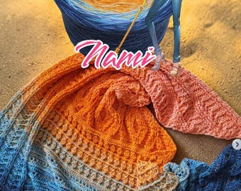 May include: A hand-crocheted shawl in shades of blue, orange, and peach, with a matching ball of yarn. The shawl features intricate stitch patterns and a scalloped edge. The word "Nami" is written on the shawl.