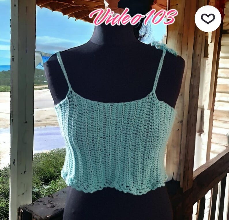 Puede incluir: Top de ganchillo azul claro con tirantes finos. El top se muestra en un maniqu&iacute; negro. El texto "Video 103" es visible en la esquina superior izquierda. El top tiene un borde festoneado.